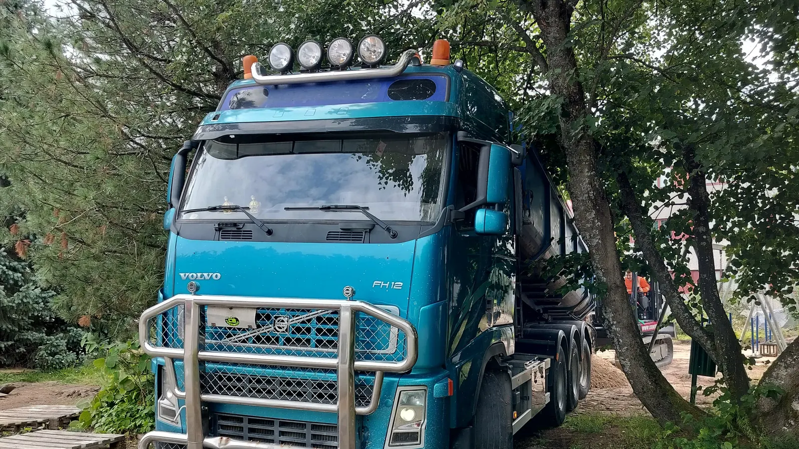 Vaihtolava-auto työmaalla puiden katveessa