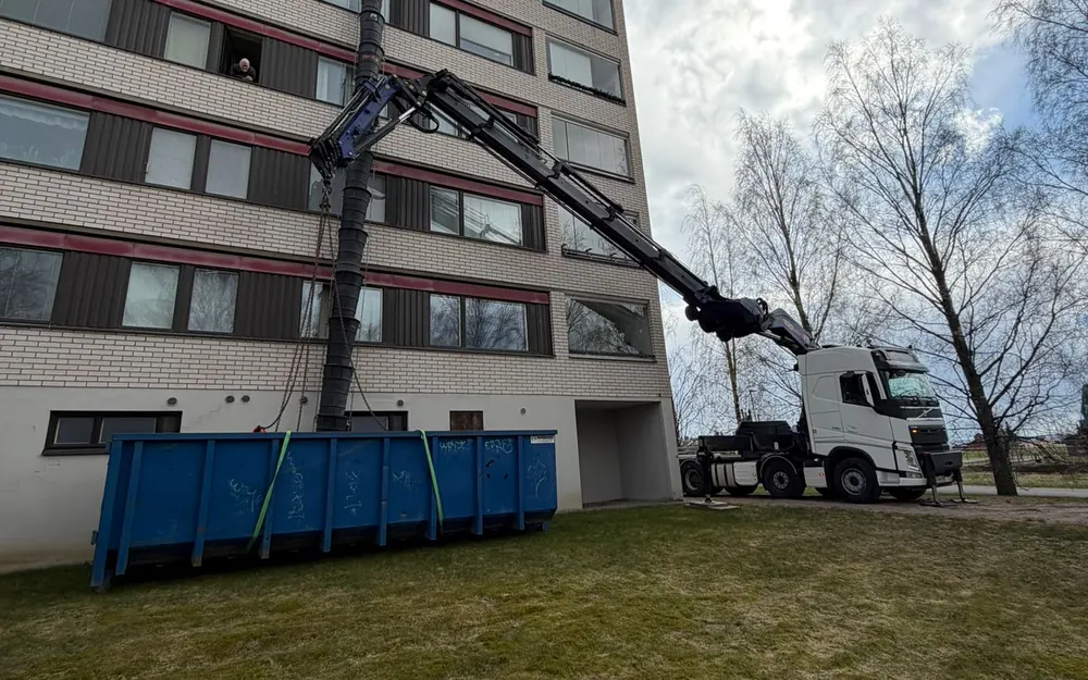 Nosturiauto nostaa vaihtolavan taloyhtiön pihalle